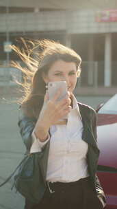 拍摄竖屏女子为电动汽车充电并使用智能手机