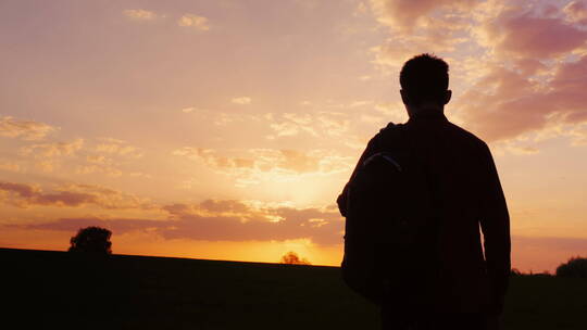 背包的青少年迎着朝阳行走的剪影