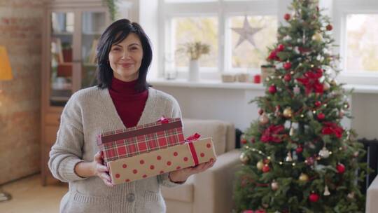 圣诞树前抱着礼盒的女人视频素材模板下载