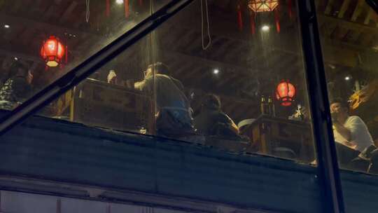 仰视夜晚落地窗火锅店吃饭聊天的人变焦