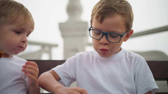 兄弟姐妹坐在一起分享薯片，而年幼的孩子手