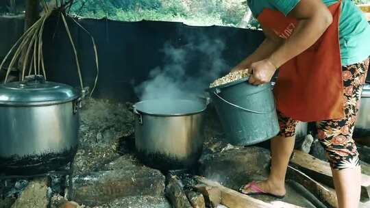 一个女人把一桶食物放在砂锅上