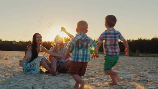 一家人坐在日落的沙滩上玩耍