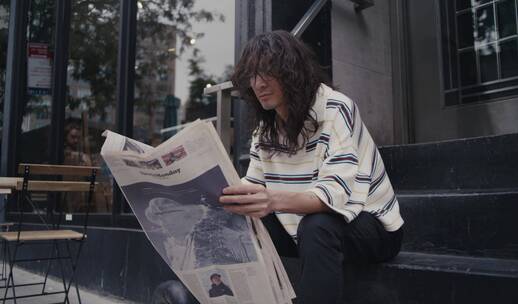 一个男人坐在街边看报纸