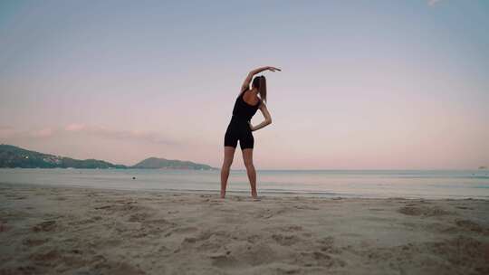 赤脚女人做瑜伽运动休息室战士在日落时在沙