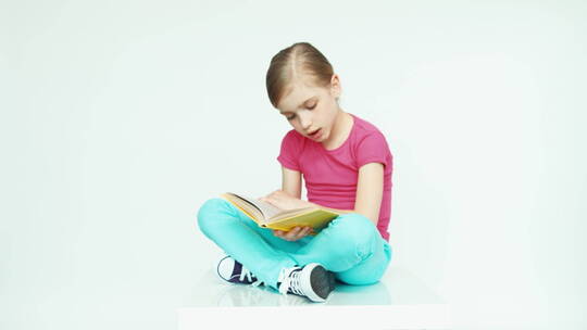 女孩盘腿坐在地上看书视频素材模板下载