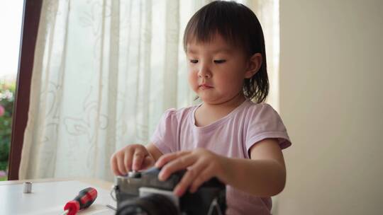 可爱的亚洲小女孩在家里摆弄相机