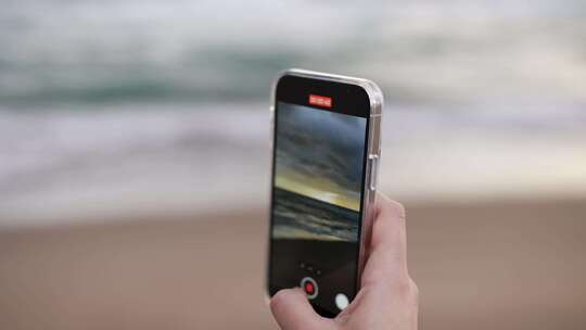 在海边用手机拍摄海浪