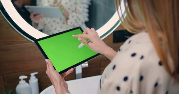 女人手里拿着一台带有绿色Chromakey屏幕的笔记本电脑。