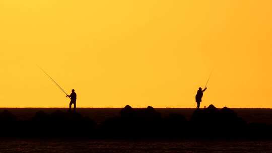 在落日余晖中钓鱼的人