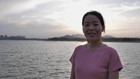 夕阳下中国女性运动后在河边喝水