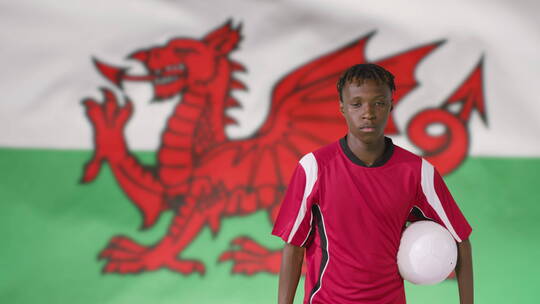 威尔士国旗前抱着足球的男人