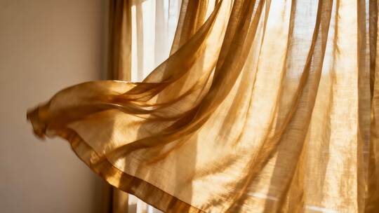 阳光投射在飘动的室内窗帘
