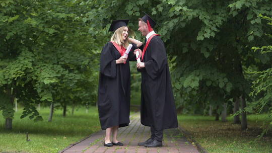 毕业生拿着毕业证书在公园里聊天