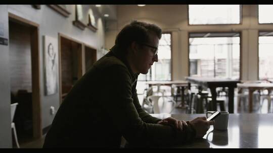 男人坐在咖啡厅用手机打字