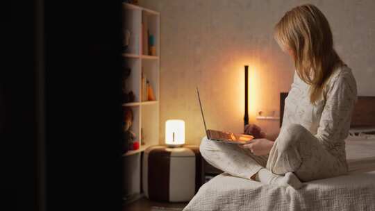 穿着睡衣的女人坐在舒适明亮卧室的床上，在视频素材模板下载