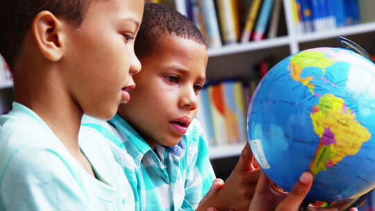 小学生在学校图书馆看地球仪