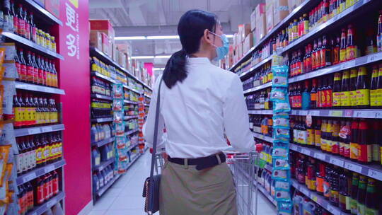 戴口罩的青年女人在超市购物