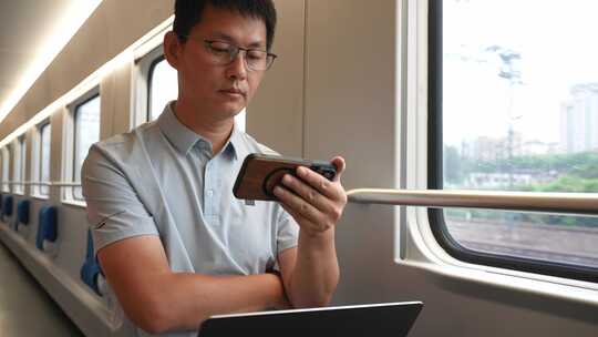 男子出差途中火车上使用笔记本电脑手机办公