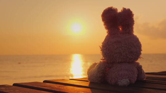 玩偶坐在码头栈桥上看日出