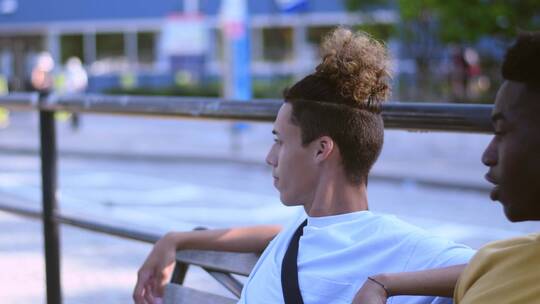 两个年轻人坐在长凳上聊天