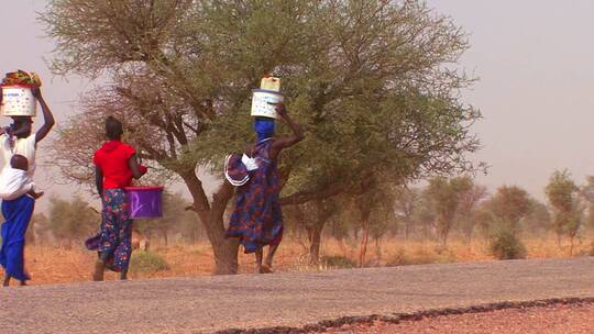 妇女头上顶着货物穿过沙漠