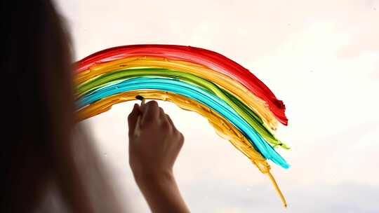 一个孩子在阳台的玻璃上画彩虹