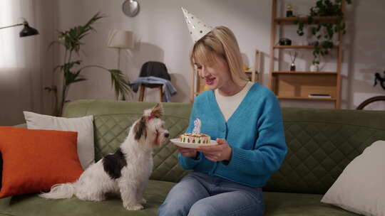 戴派对帽的女人在室内用蛋糕庆祝狗的生日