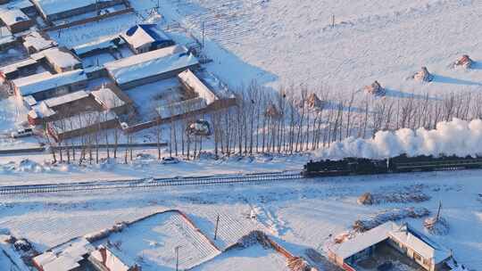 航拍中国东北冬季雪景中的蒸汽火车穿过村庄