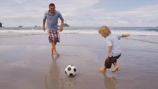 父子在沙滩上踢足球
