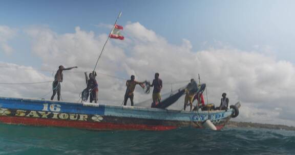 渔民在帆船上抛下渔网