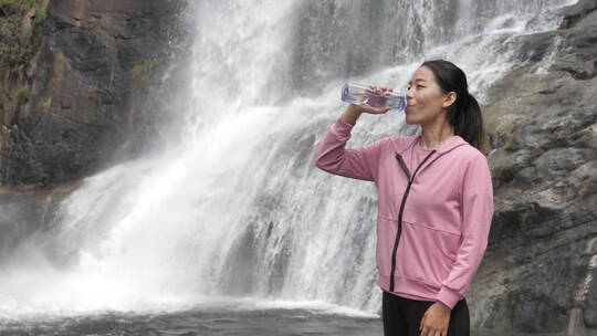 亚洲中国人女性在瀑布下喝水饮用水