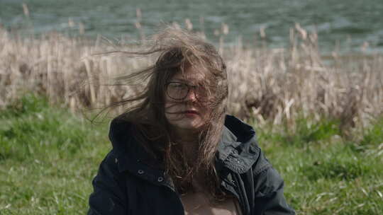 强风吹着戴眼镜的悲伤女人的头发