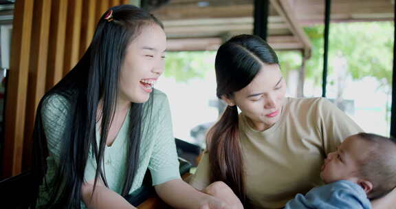 两个年轻的亚洲女人在咖啡馆里开心地和一个