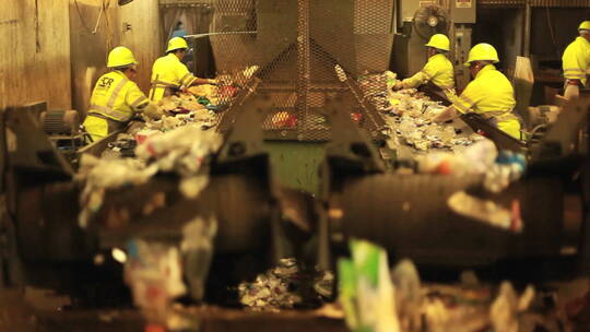 回收中心的工人在传送带上分垃圾