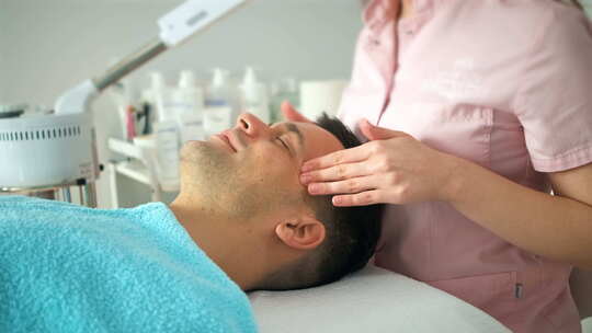 美容师在美容院给一个男人做面部护理。