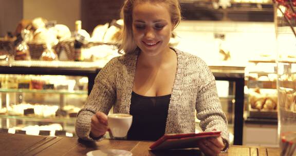 女人坐在咖啡馆喝咖啡使用平板电脑