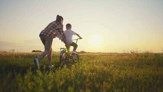 妈妈教儿子在乡村骑自行车暑假在田野之间看