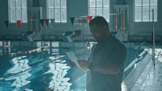 出生男游泳教练赛前查看运动员名单