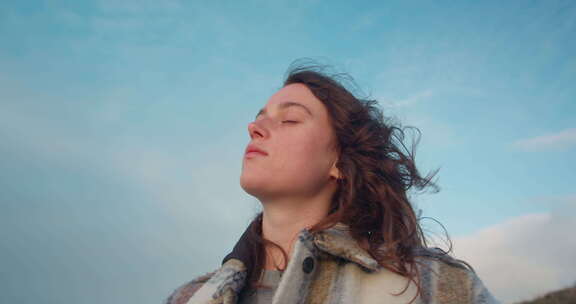 年轻女子的肖像在微风中看天空