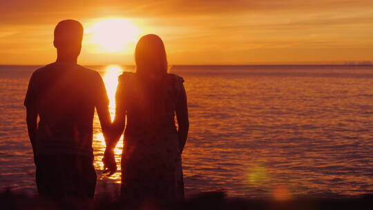 夫妇牵着手欣赏海上日落