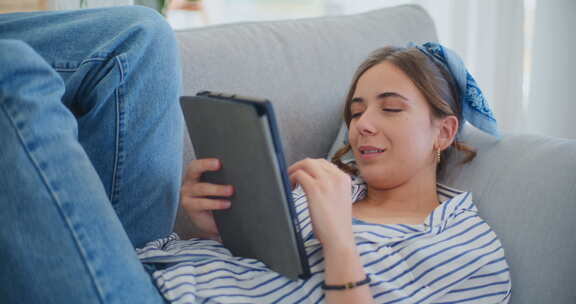 微笑的女人在沙发上放松，同时浏览互联网
