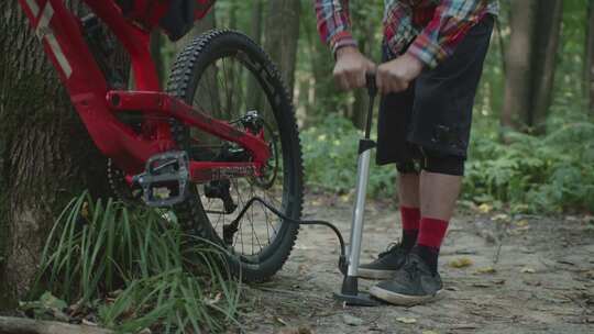 树林中男子给山地自行车打气