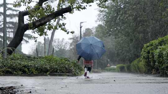 小女孩撑着伞在雨中奔跑