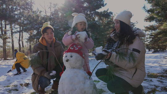 快乐家庭在雪地里堆雪人