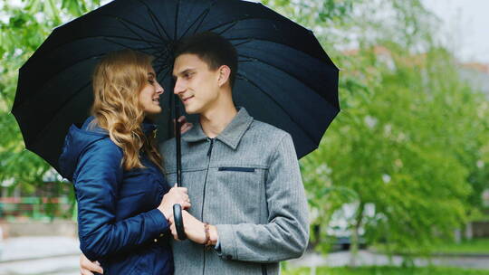 街边撑伞的年轻夫妇在聊天