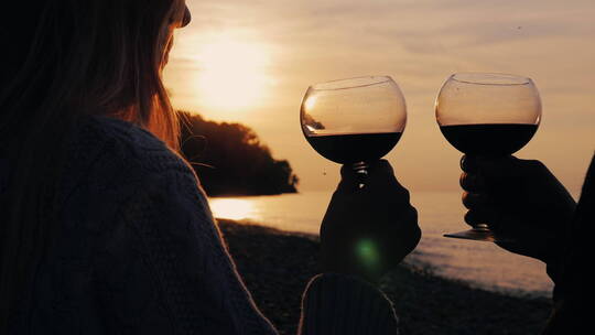 一对年轻夫妇在湖边日落时喝酒的剪影