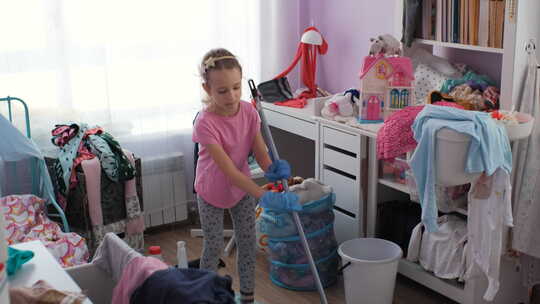 小女孩用扫帚打扫房间里的地板