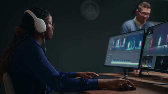 在工作室后期制作中，女性视频编辑器通过计算机中的电影编辑软件制作剪辑