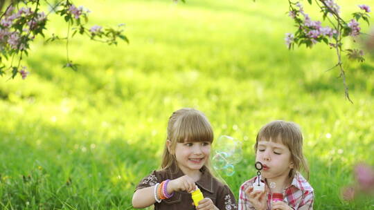 两个小女孩在草地上吹泡泡